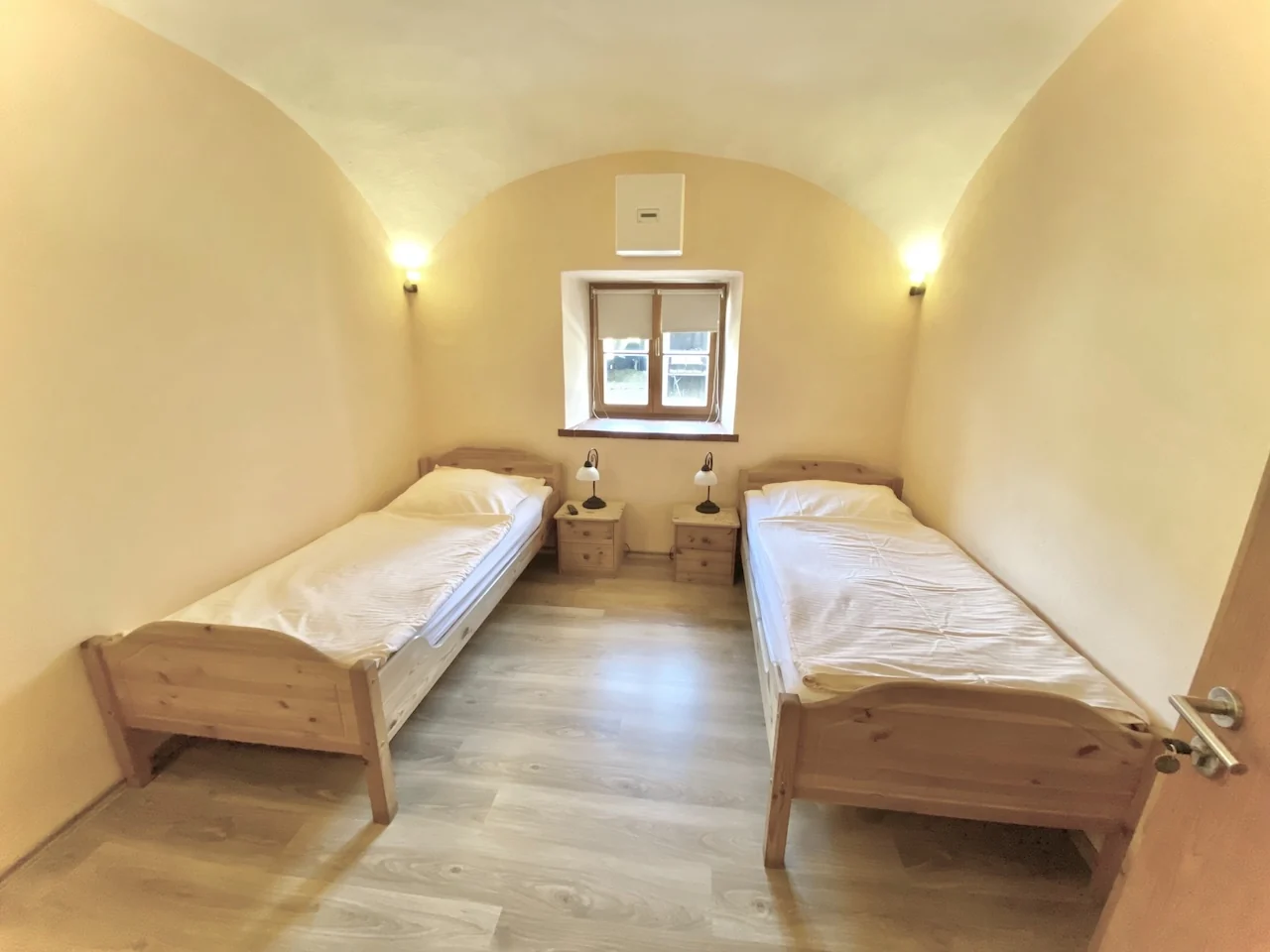 Nichtraucher-Zweibettzimmer auf der Laurent Ranch in Gottfrieding mit Holzbetten, Nachttischlampen und Gewölbedecke