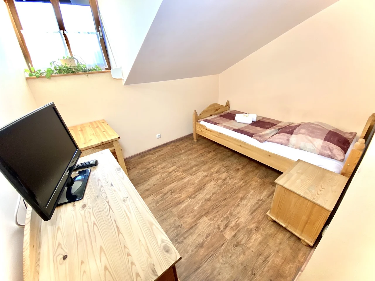 Einzelzimmer auf der Laurent Ranch in Gottfrieding mit schmalem Bett unter der Dachschräge, Nachttisch und Fenster