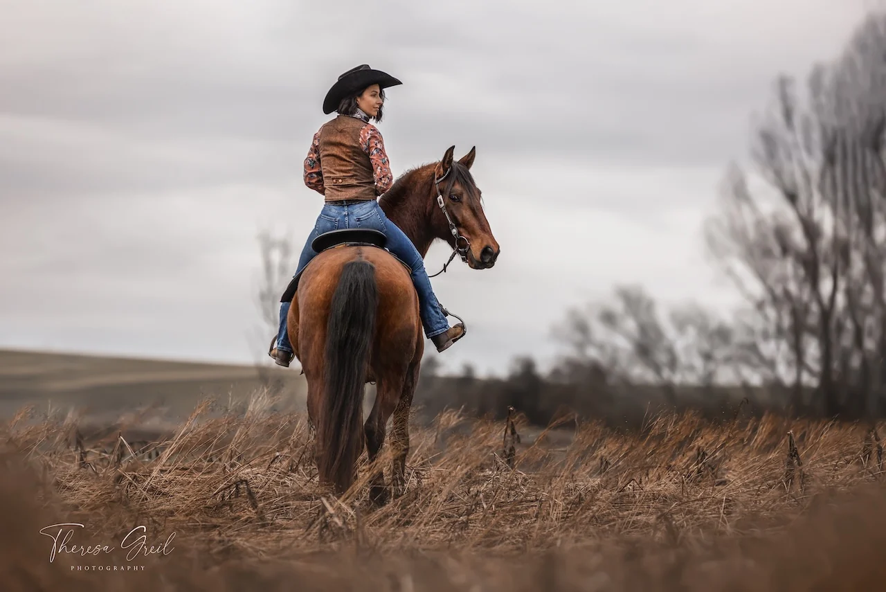 Selina Hempel auf einem braunen Pferd im abgeernteten Feld bei der Laurent Ranch in Niederbayern
